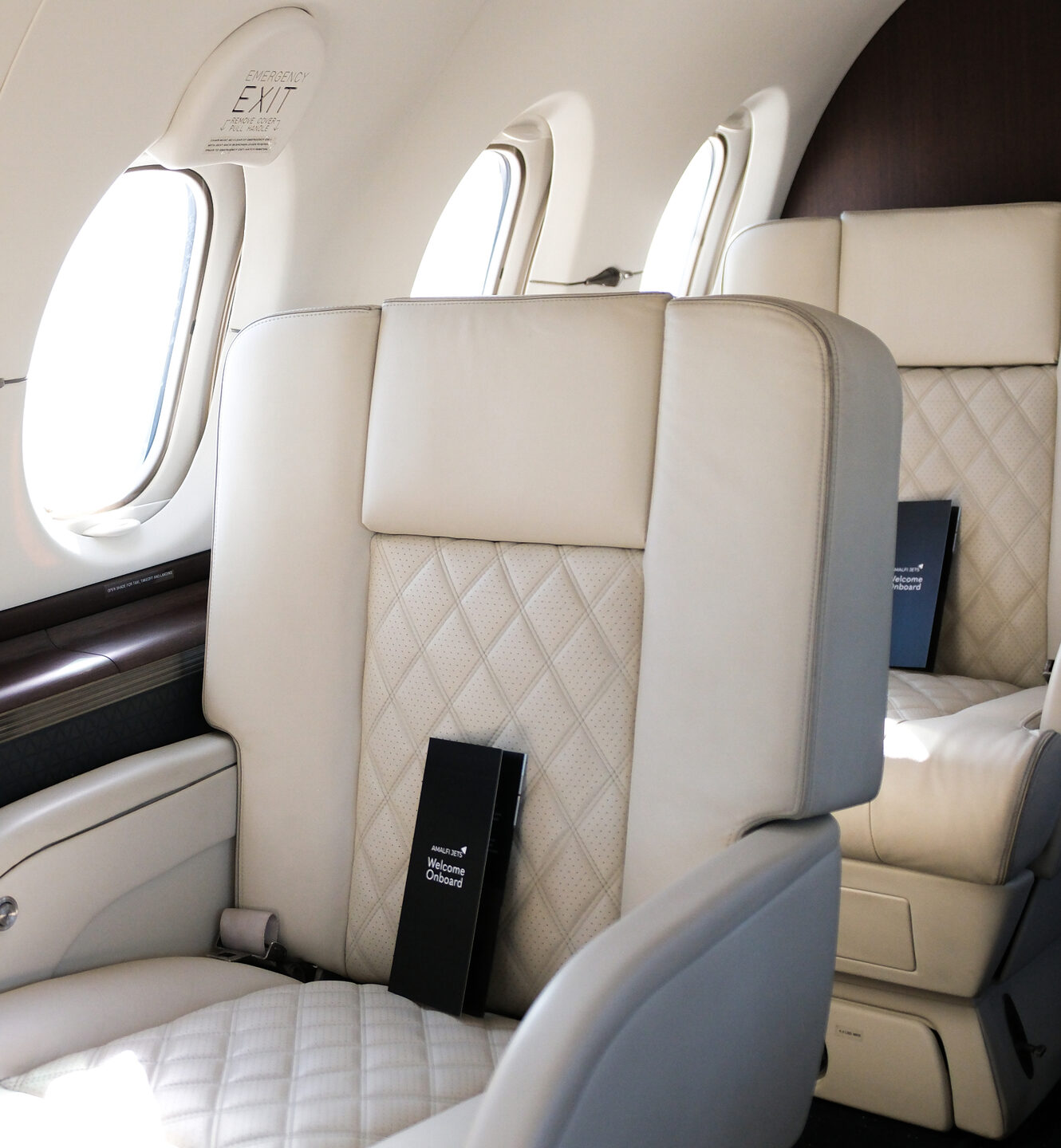 Quilted cream leather seat in a private jet cabin beside an oval window.