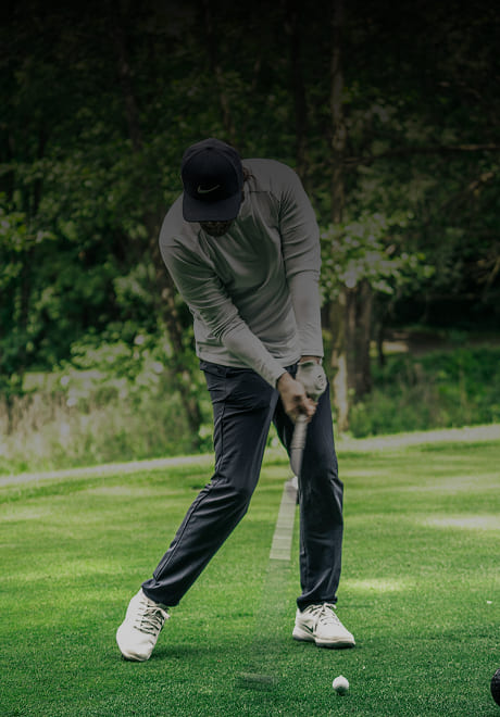Golfer teeing off on a peaceful, tree-lined golf course during a private golf experience