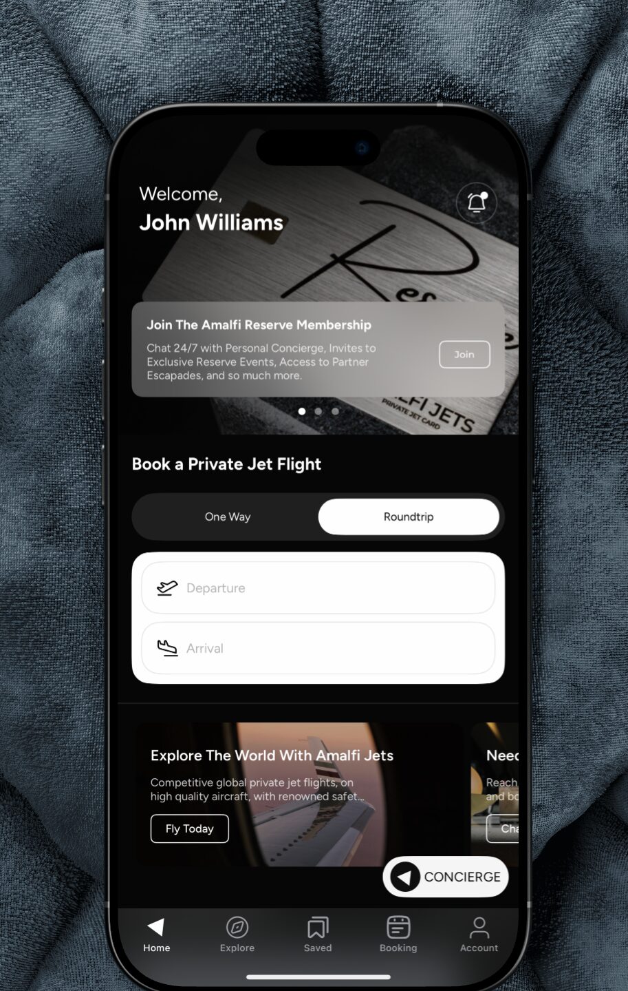 A hand holding a phone showing the Amalfi Jets app home screen with a personal welcome and a book-a-flight form.