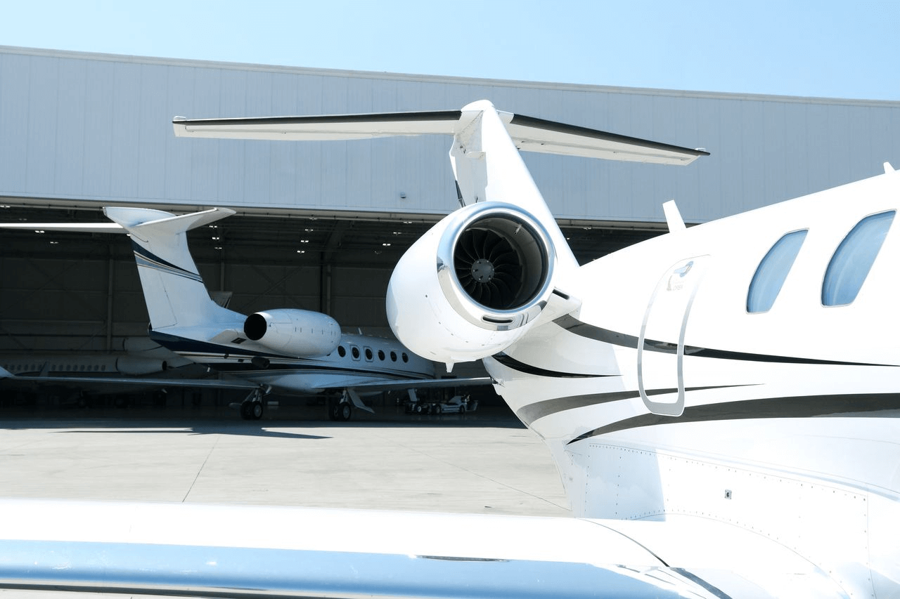 Close-up of a Cessna Citation private jet with polished engines parked beside another aircraft inside a hangar.