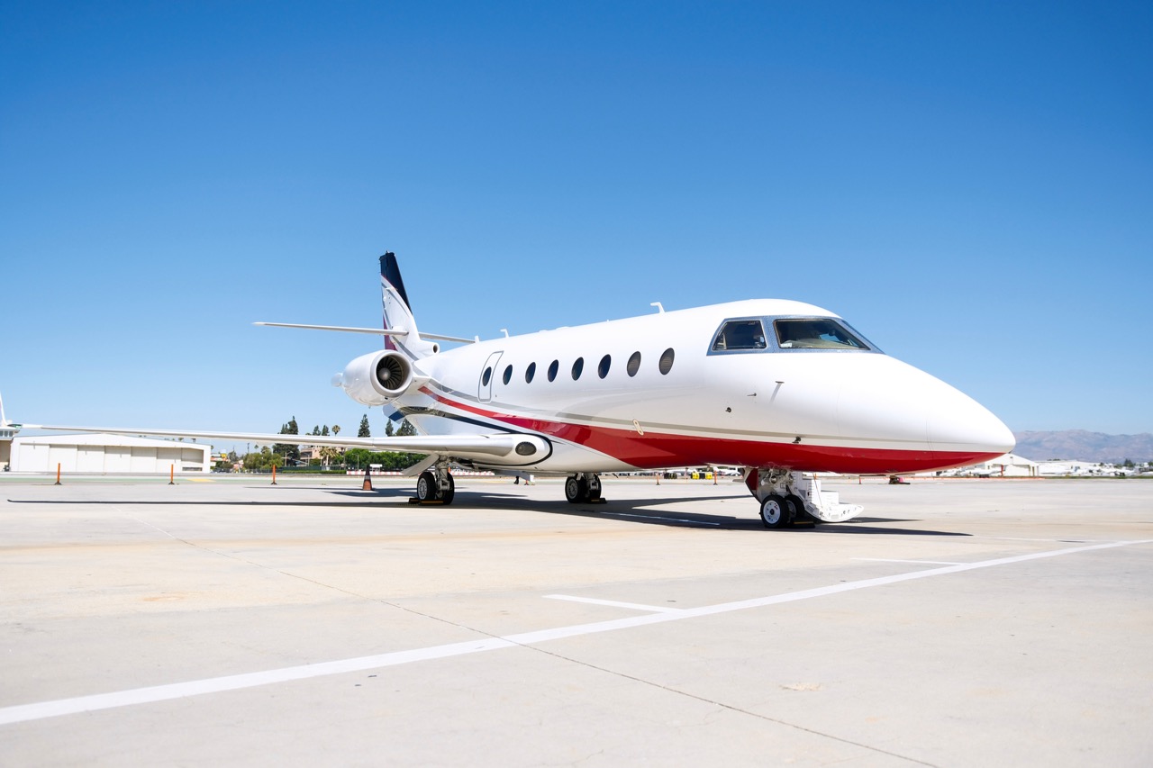 Challenger 300 private jet parked on runway with cabin door open, twin engines, and sleek exterior design.