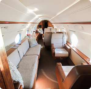 Amalfi Jets Gulfstream cabin interior with grey leather seating, wood accents, and natural light.