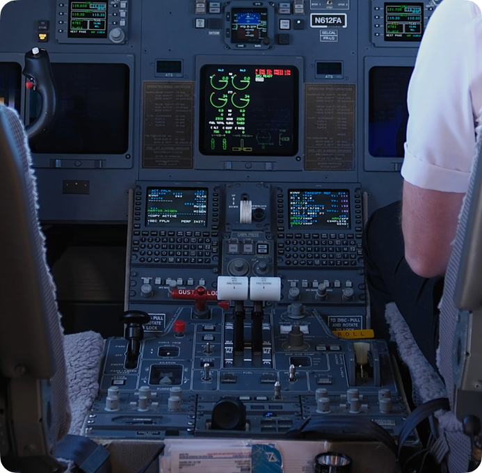 Close-up view of the Bombardier Challenger 604 flight deck with active navigation screens and engine control panels.