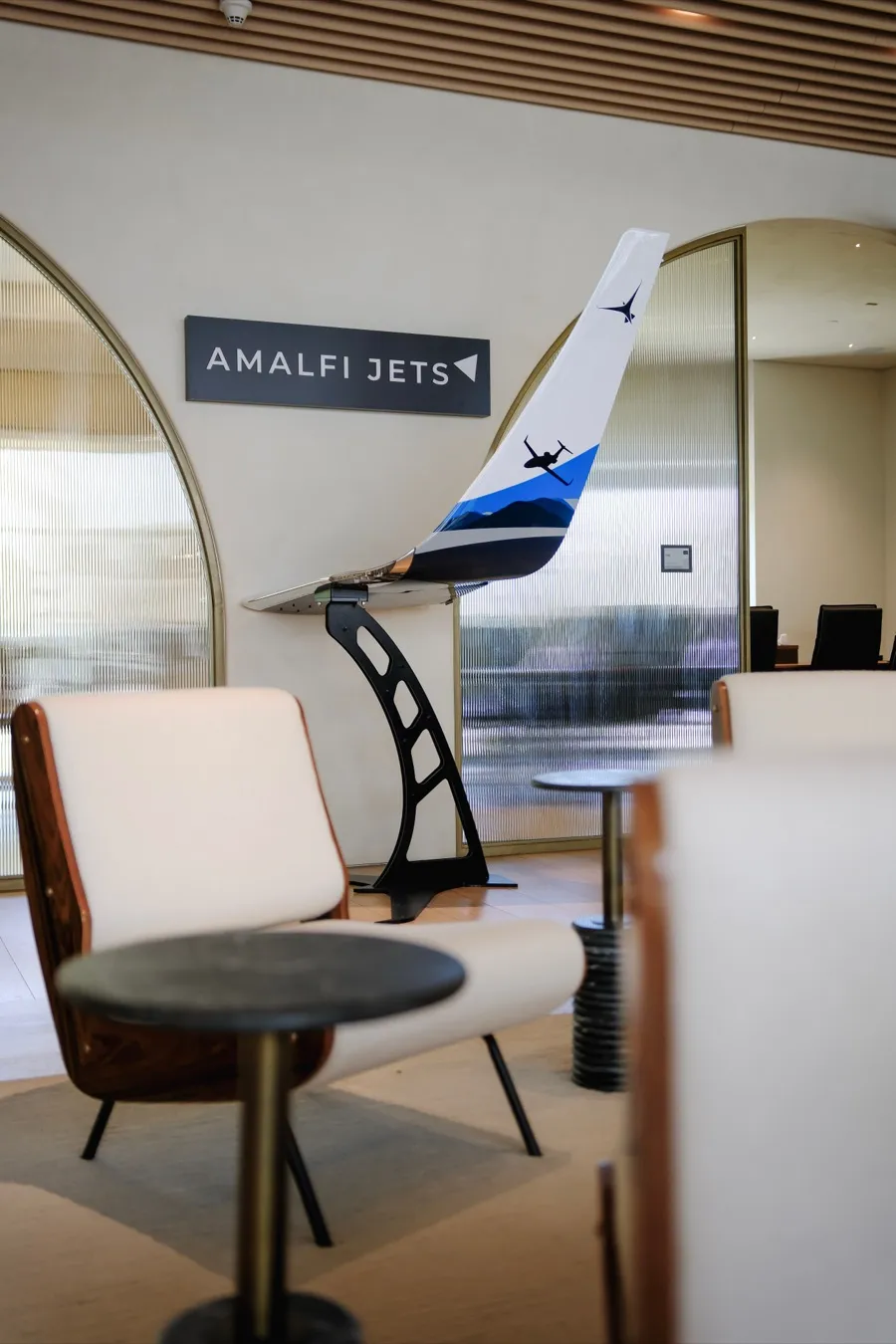 A model Amalfi Jets aircraft tail on a plinth beside lounge seating in the Amalfi Jets office.