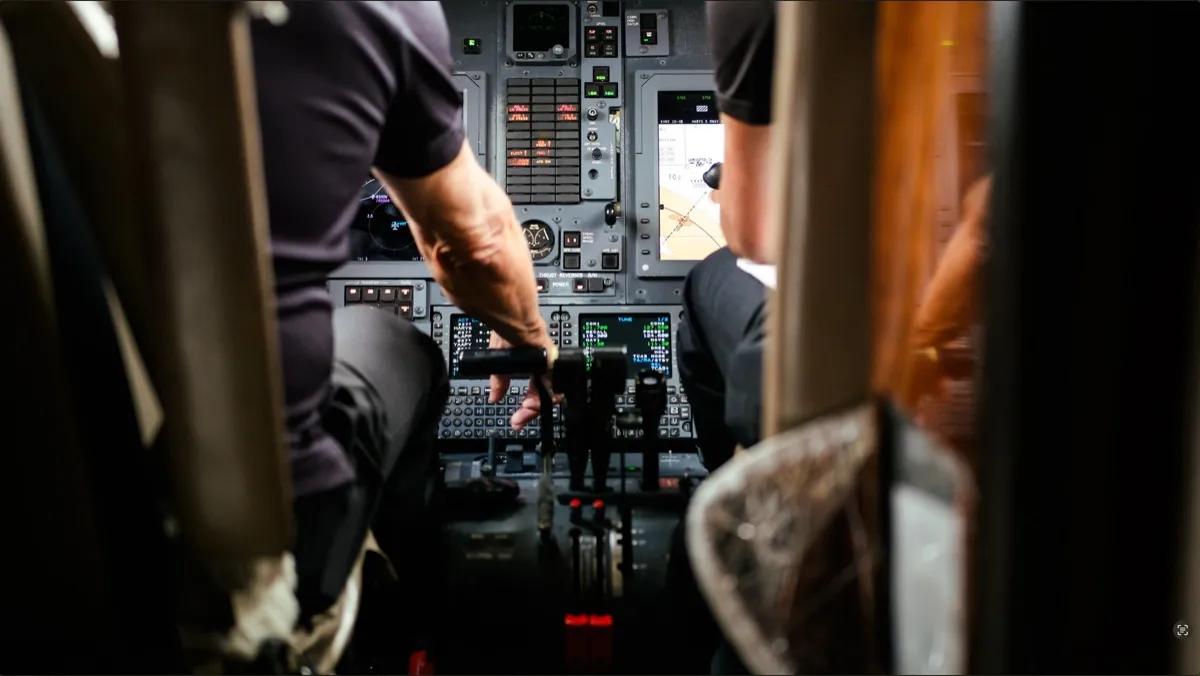 Two pilots at the controls of a private jet flight deck with the avionics displays lit.