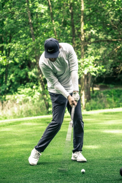 Golfer teeing off on a peaceful, tree-lined golf course during a private golf experience