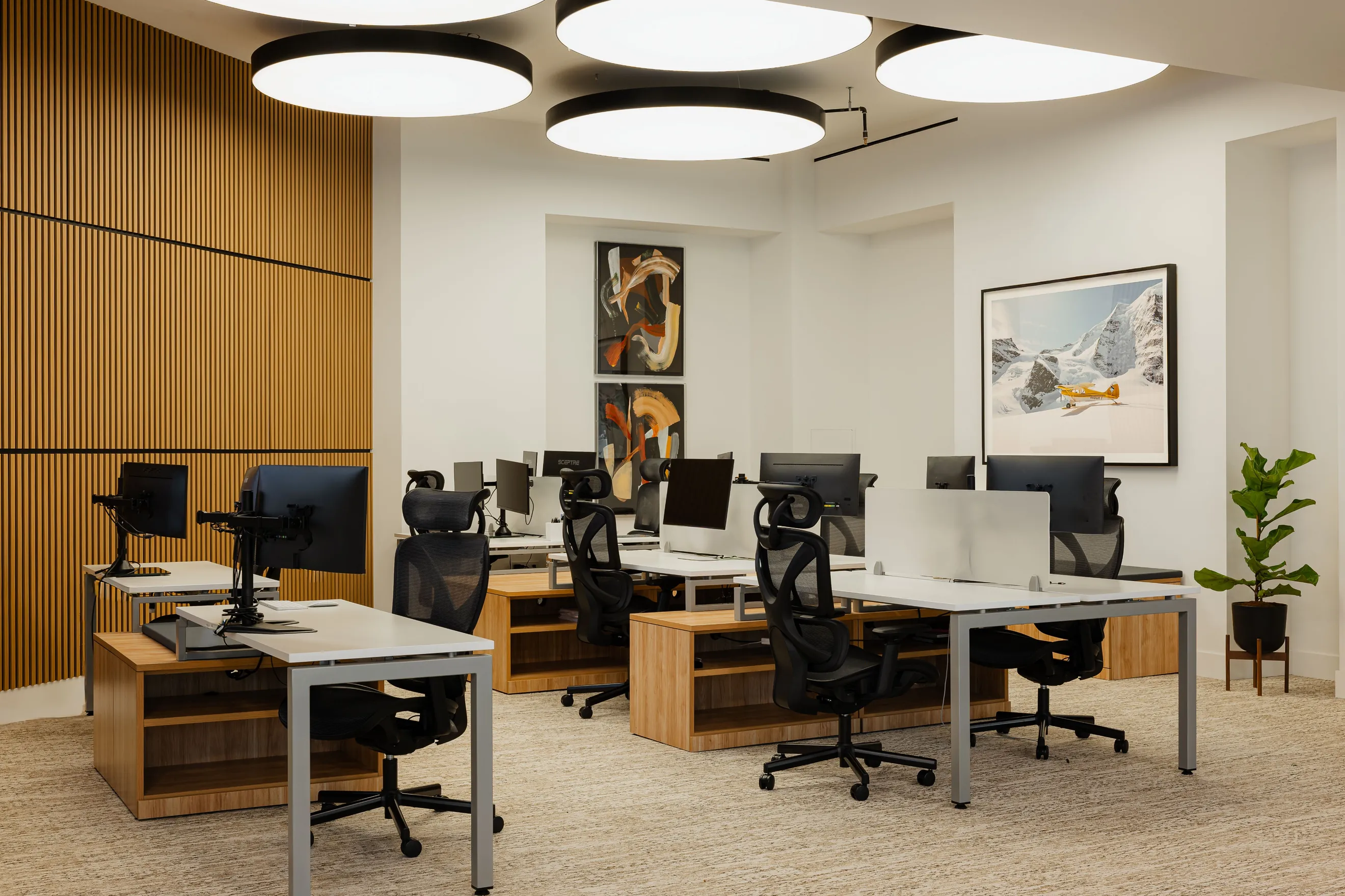 The Amalfi Jets engineering floor: rows of desks with monitors, ergonomic chairs and framed aviation artwork.